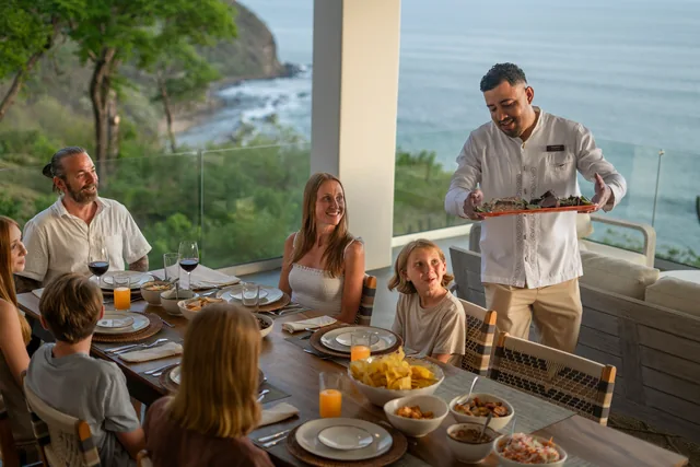 A chef serving a family at their ocean-view accommodation